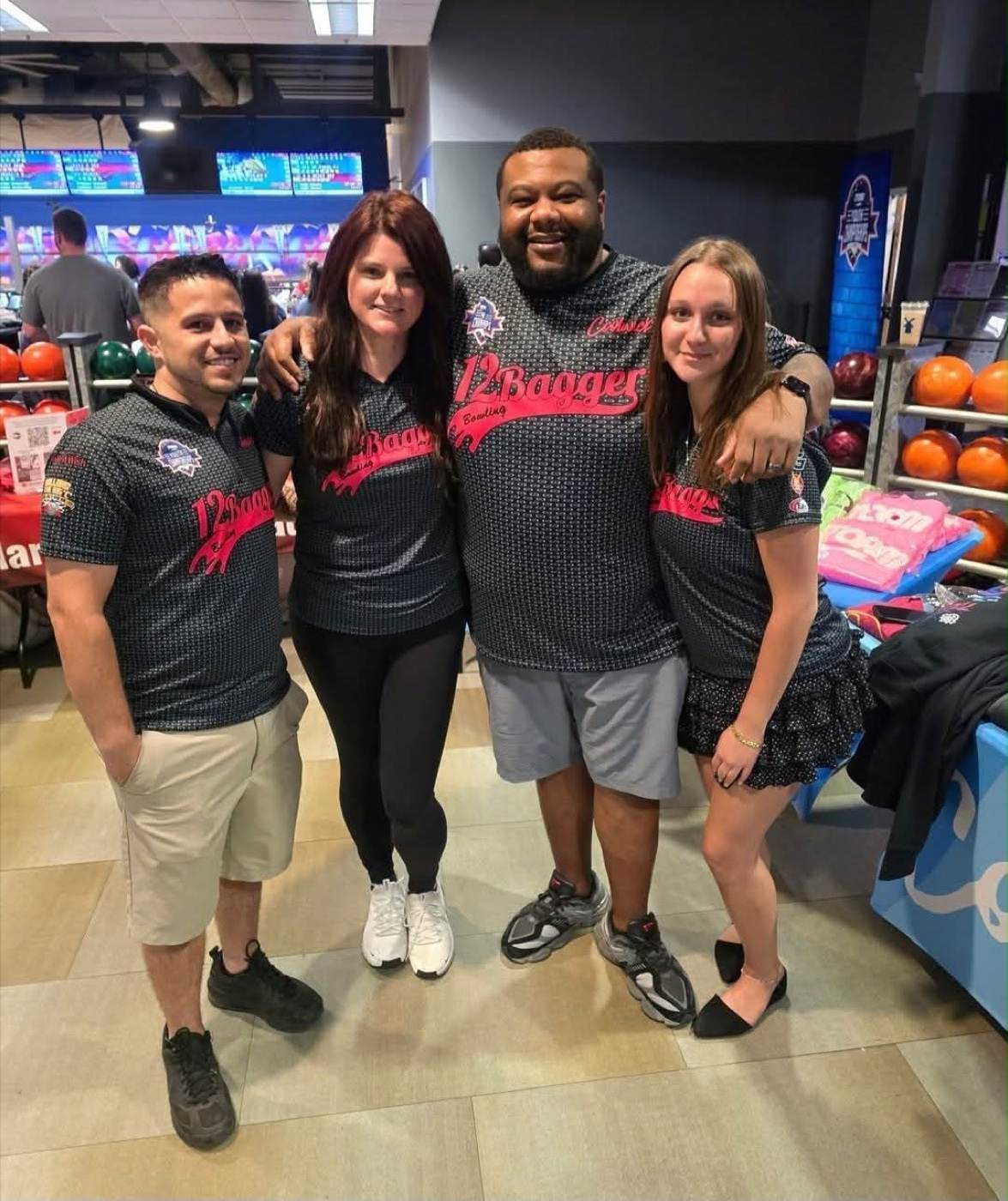 A four-person team in matching black and red 12Bagger jerseys at their bowling centre