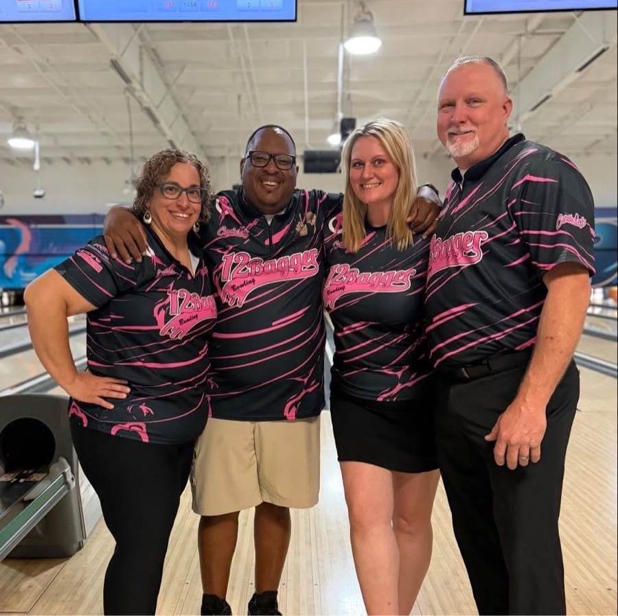 Four bowlers in black and pink 12Bagger jerseys standing together on the approach