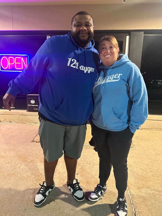 Two bowlers in 12Bagger hoodies outside a bowling centre at night