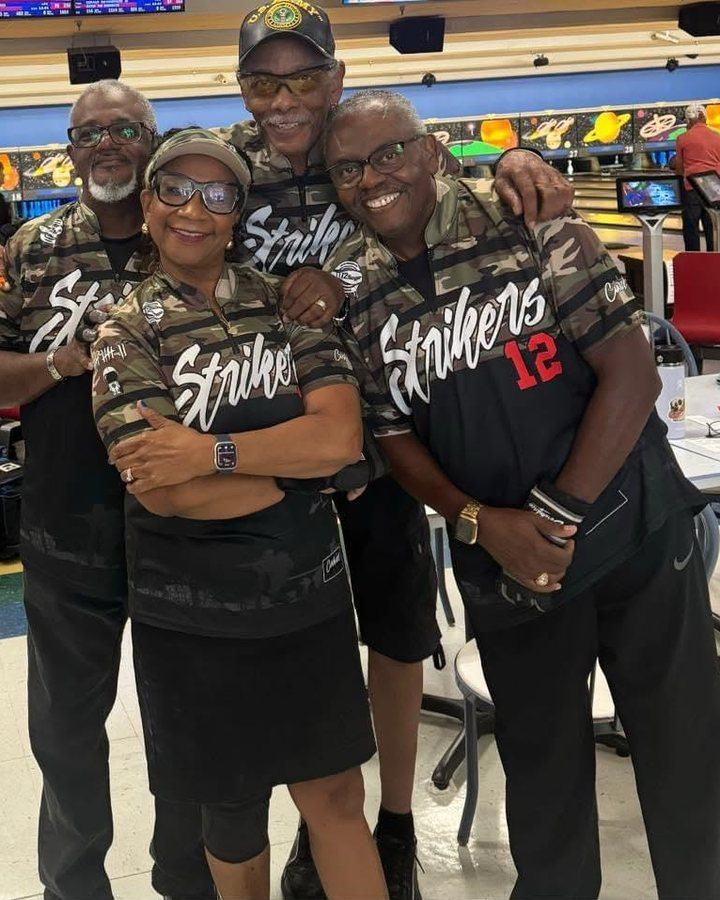 Four bowlers in matching Strikers camo jerseys with arms around each other